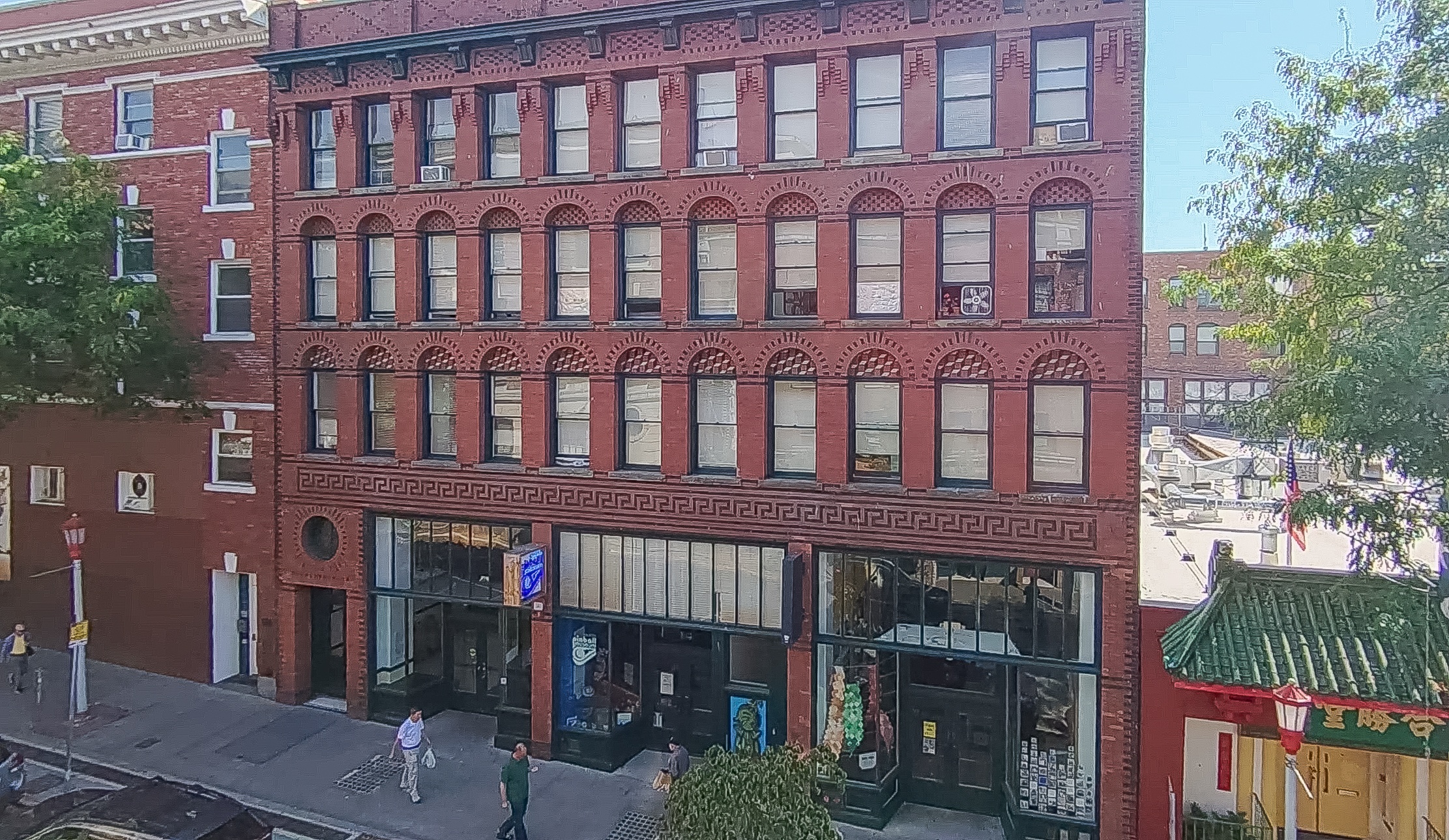A red brick building with a green roof and a blue sign on the ground floor.